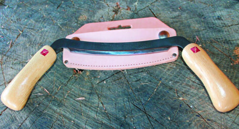 a drawknife laid on a stump on top of a pink protective cover.
